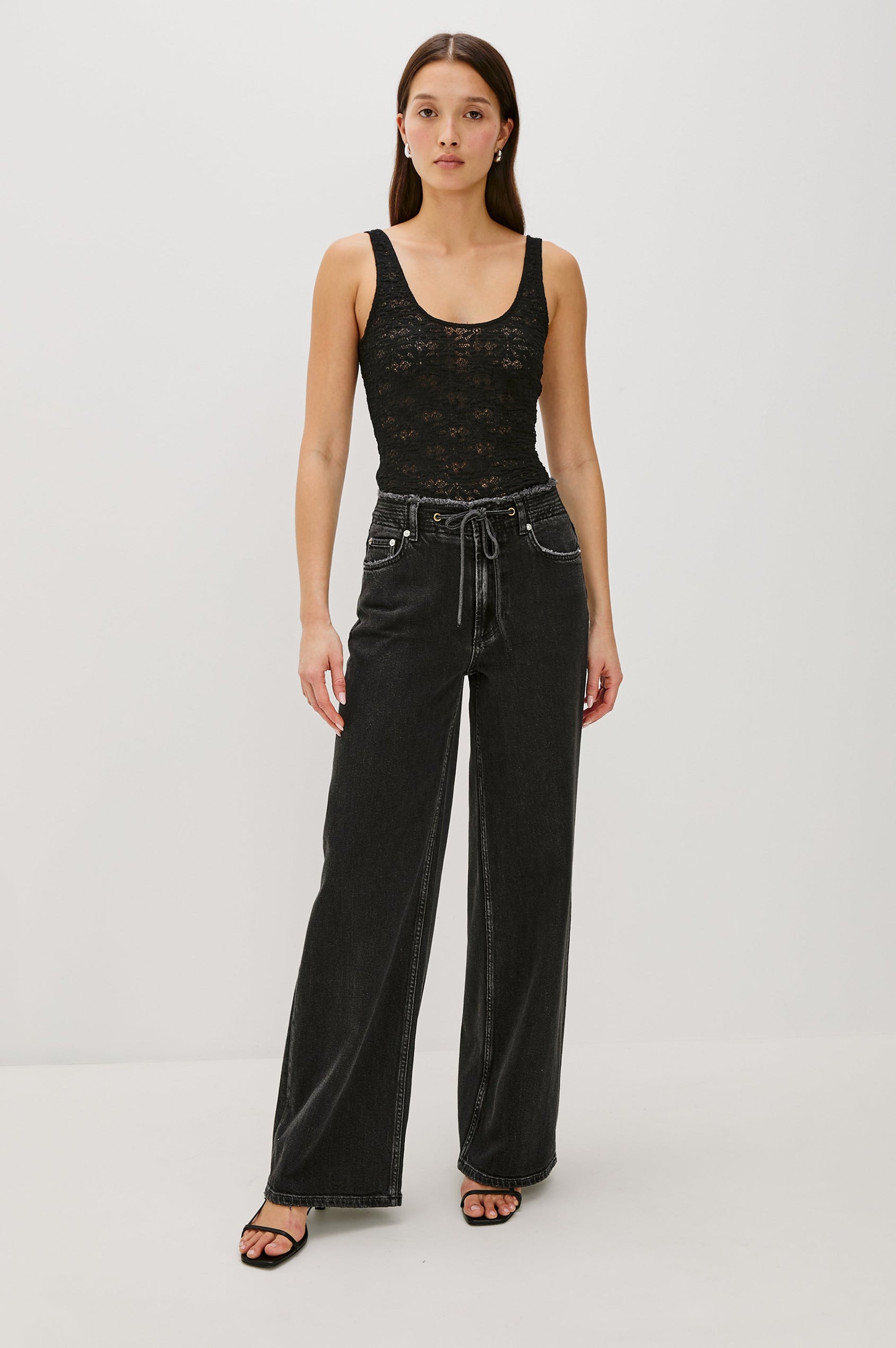 Donya is a sheer, unlined tank top with a scoop neckline in lace fabrication for added texture in Black Lace Colorway - Full Body Front View Featured on Model