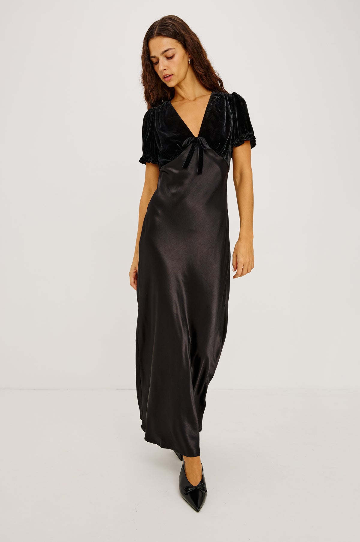 Dory Maxi Dress With V-Neckline and Adjustable Center Bust Ties, Short Puff Sleeves, Satin Back Crepe Skirt, and Back Zipper Closure in Black Colorway - Upper Body Front View Featured on Model.