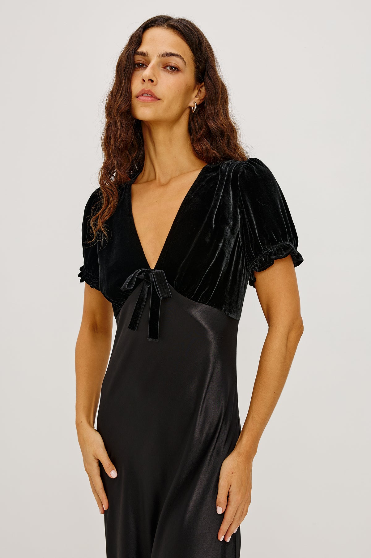 Dory Maxi Dress With V-Neckline and Adjustable Center Bust Ties, Short Puff Sleeves, Satin Back Crepe Skirt, and Back Zipper Closure in Black Colorway - Front View Featured on Model.