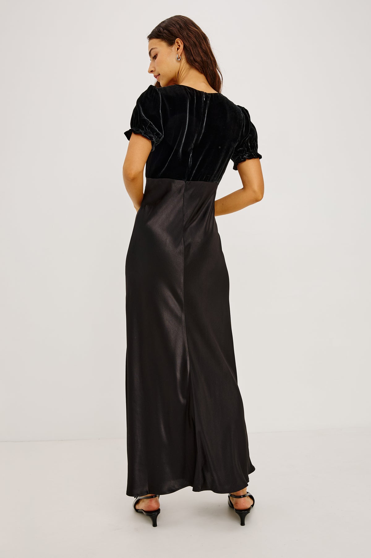 Dory Maxi Dress With V-Neckline and Adjustable Center Bust Ties, Short Puff Sleeves, Satin Back Crepe Skirt, and Back Zipper Closure in Black Colorway - Upper Body Back View Featured on Model.
