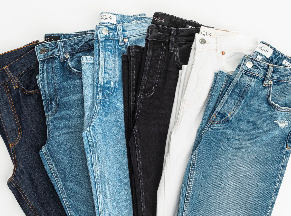 MULTIPLE PAIRS OF JEANS FOLDED AND LAYING NEXT TO EACH OTHER