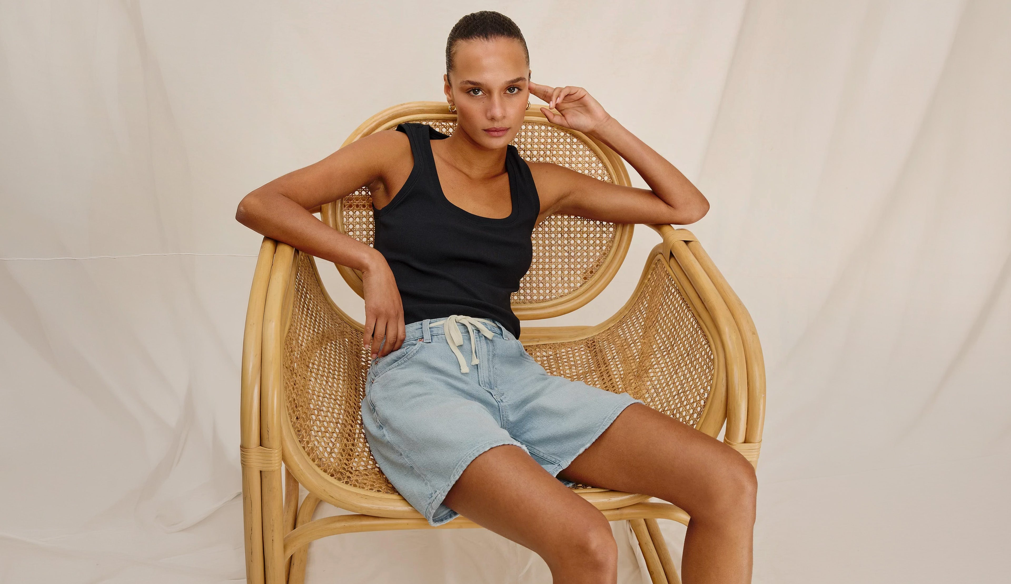 Woman wearing a black tank top and light blue denim shorts