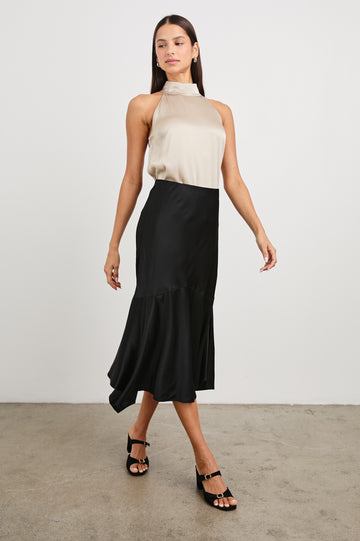 Edwina Midi Skirt with a Handkerchief Hem in Black Colorway - Front Full Body View Featured on Model