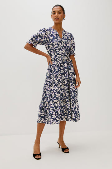 Eliana Midi Dress with Elbow Length Sleeves with Elasticated Ruffle Hem, V-Neck, 3-Button Front, Self Waist Tie and Tiered Skirt in Navy Vines Colorway. Front Full Body View Featured on Model.