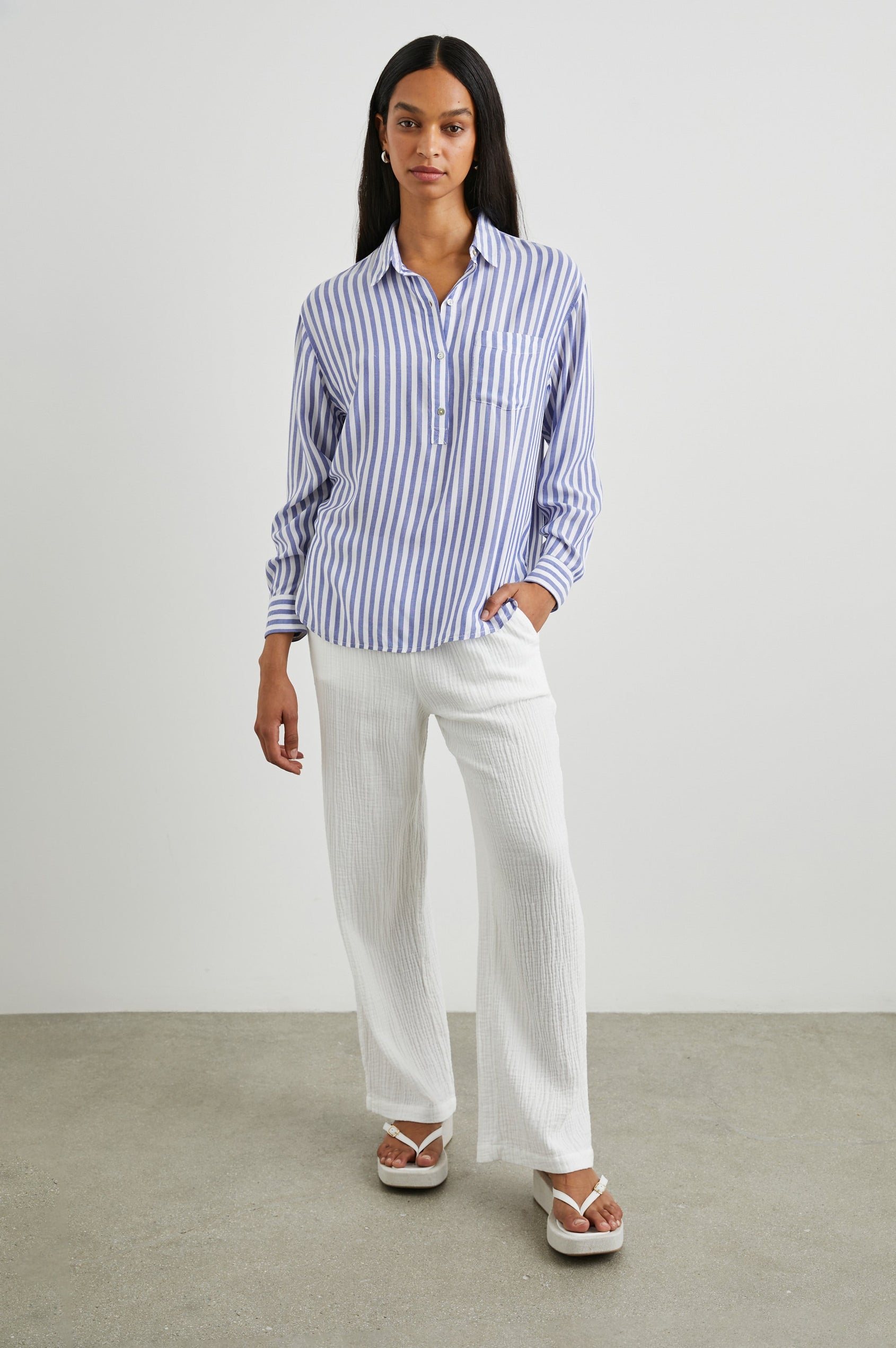 Elle Long Sleeve Shirt with a Four Button Placket, Buttoned Cuffs, a Chest Pocket and a Collar in Blue White Stripe Colorway, Vertical Stripes - Front Full Body View Featured on Model