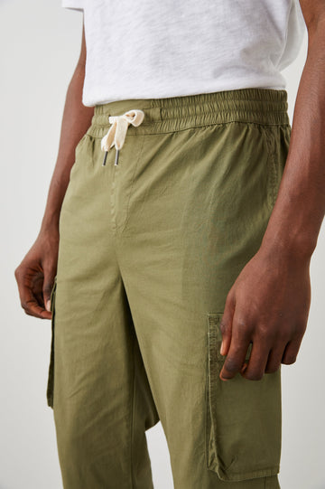 Emmerson Pants with a Drawstring Waist, Two Front Pockets, Two Side Flap Pockets and Two Back Welt Pockets in Olive Colorway - Front View Featured on Model