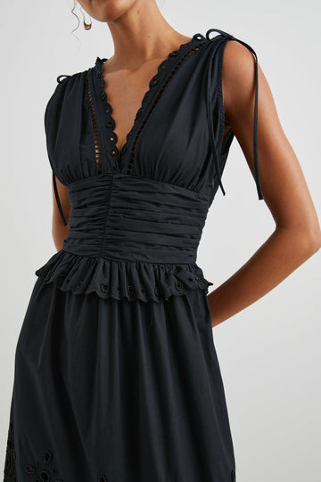 Esmeralda Sleeveless Maxi Dress with a Deep V Neck, a Ruched Waistband, Drawstrings Across the Shoulder Straps, Scalloped Trim with Cutouts on the Bodice, a Tiered Skirt, and an Eyelet Design along the Hem in Black Colorway - Front View Featured on Model 