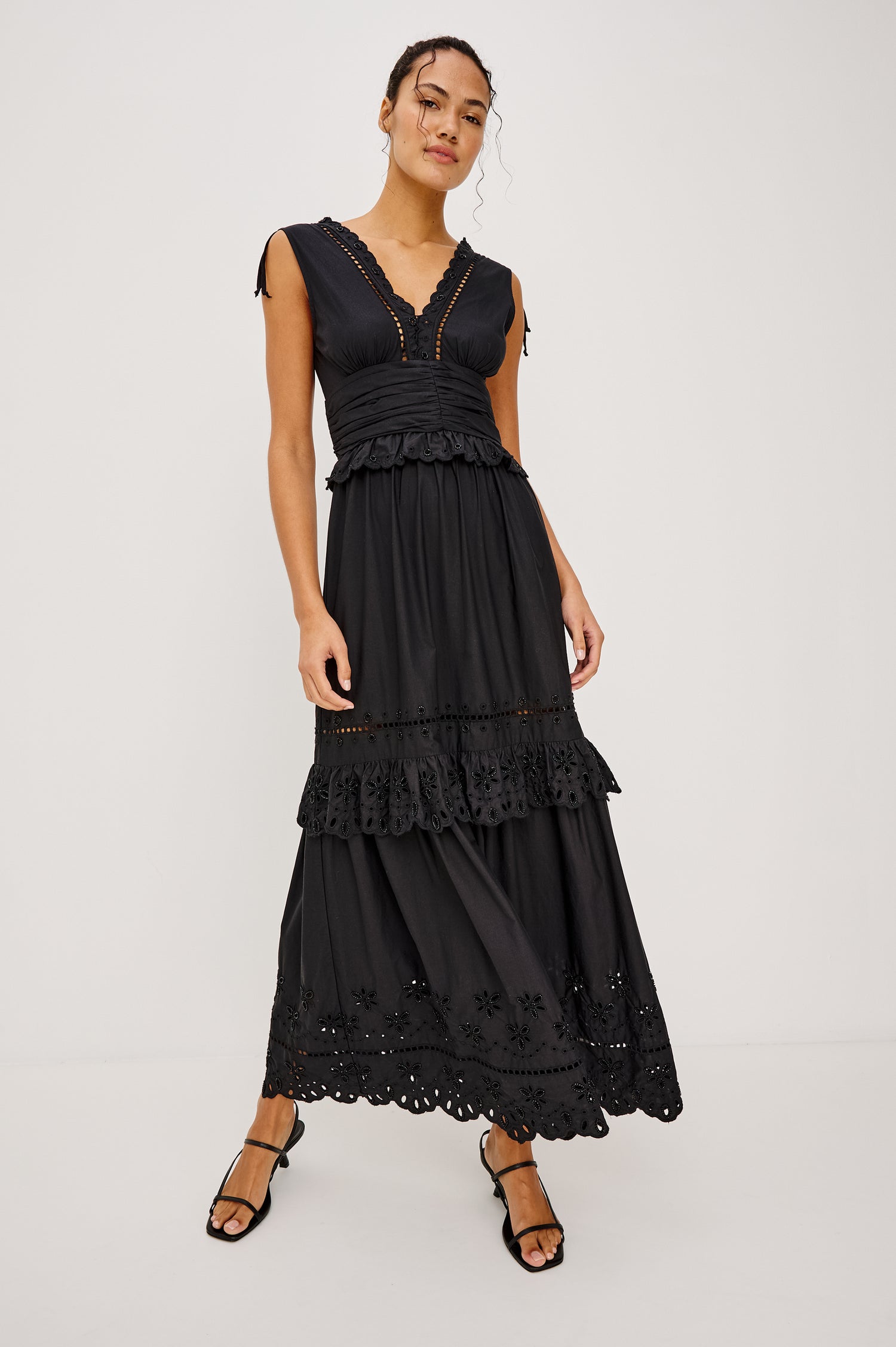 Esmeralda maxi dress has a plunging v-neckline, tiered skirt and intricate beading details in black colorway. Full body front view featured on model.