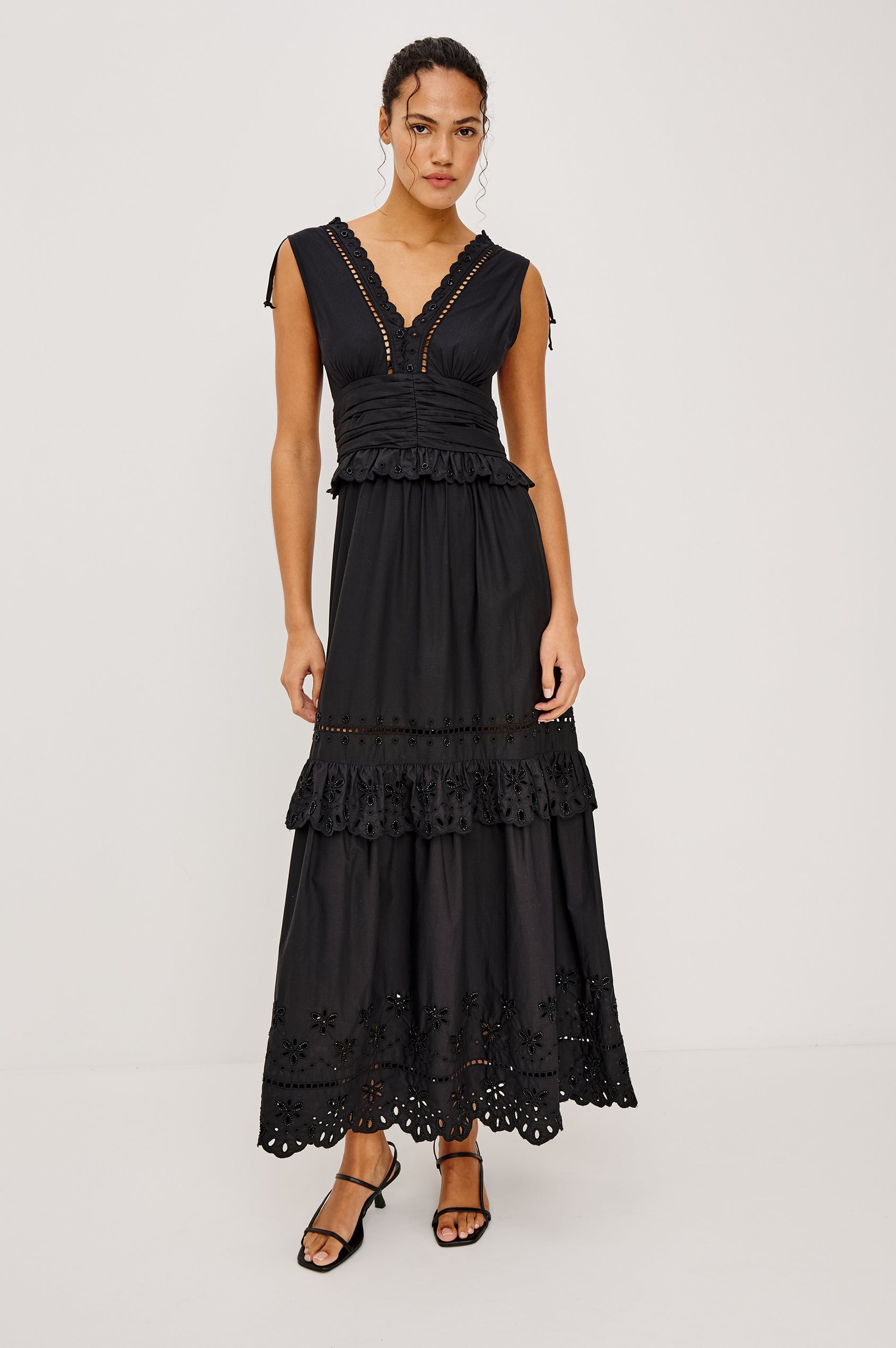 Esmeralda maxi dress has a plunging v-neckline, tiered skirt and intricate beading details in black colorway. Full body front view featured on model.