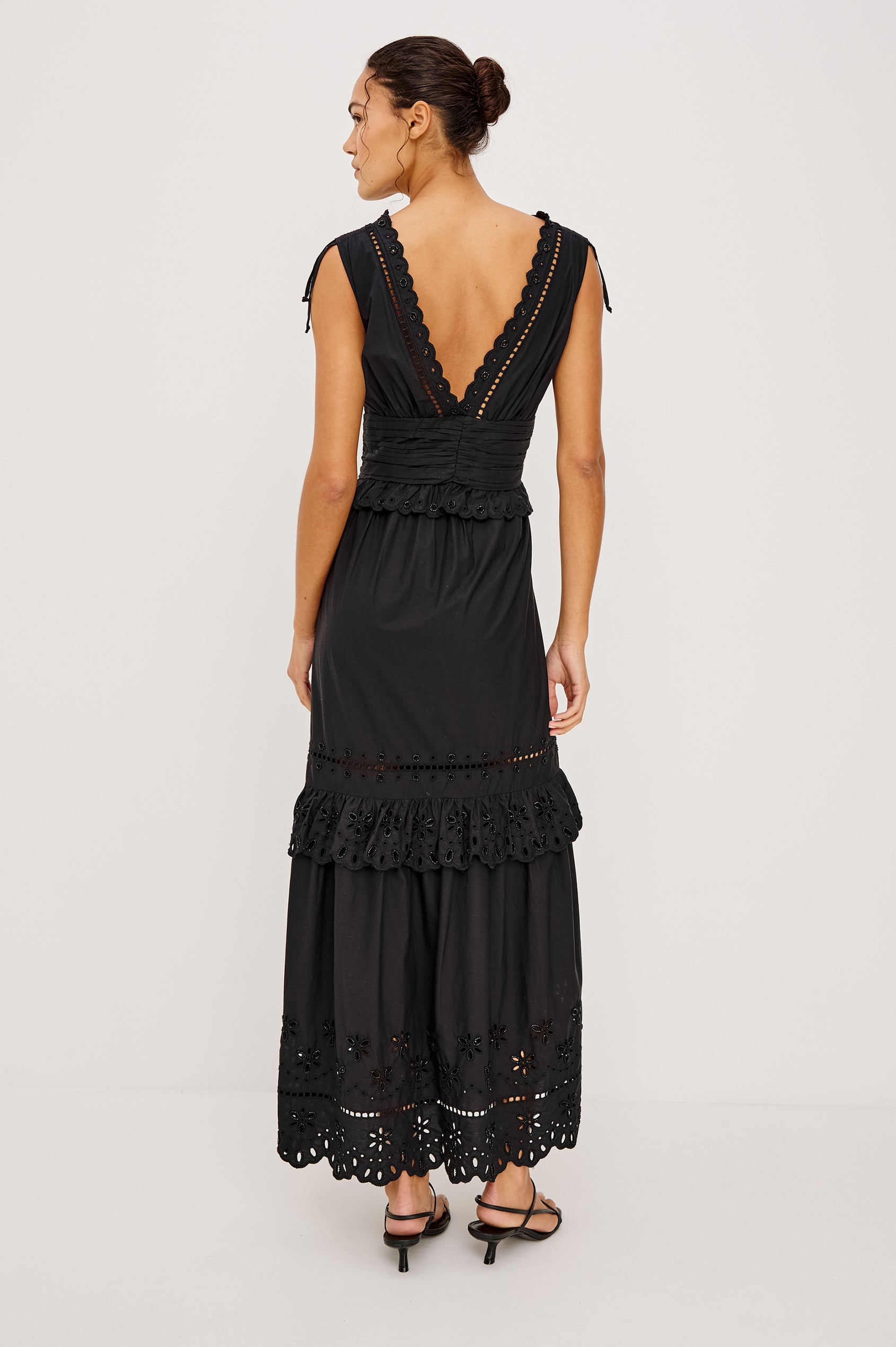 Esmeralda maxi dress has a plunging v-neckline, tiered skirt and intricate beading details in black colorway. Full body front view featured on model.