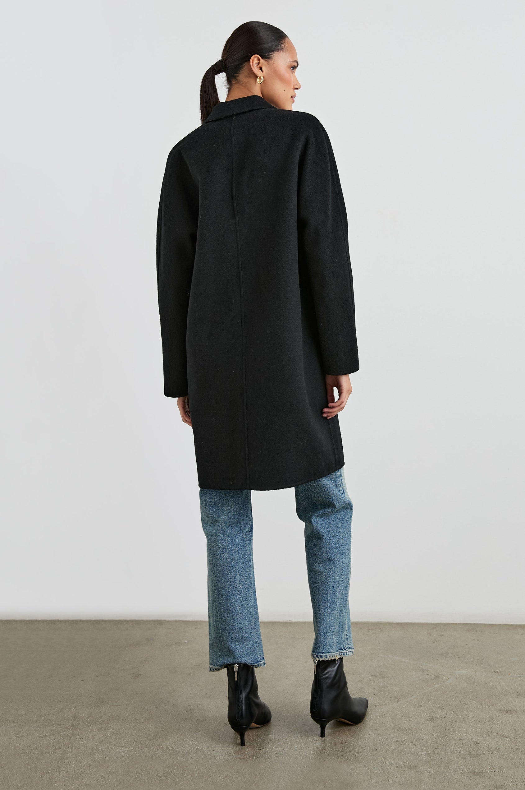 Everest Mid-Thigh Length Coat with Single Button Closure, Notched Lapels and Front Patch Pockets in Black Colorway - Back Full Body View Featured on Model