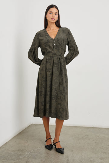 Fabian Long Sleeve Midi Dress with a V Neck with Three Buttons, a Fabric Tie at the Waist, Button Cuffs and Light Ruching on the Sleeves in Olive Pebble Colorway, Black Pebble Pattern on Olive - Front Full Body View Featured on Model