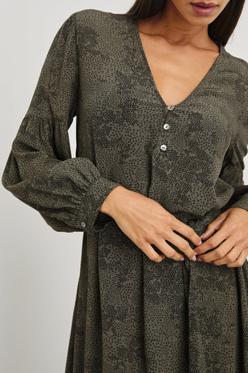 Fabian Long Sleeve Midi Dress with a V Neck with Three Buttons, a Fabric Tie at the Waist, Button Cuffs and Light Ruching on the Sleeves in Olive Pebble Colorway, Black Pebble Pattern on Olive - Front View Featured on Model