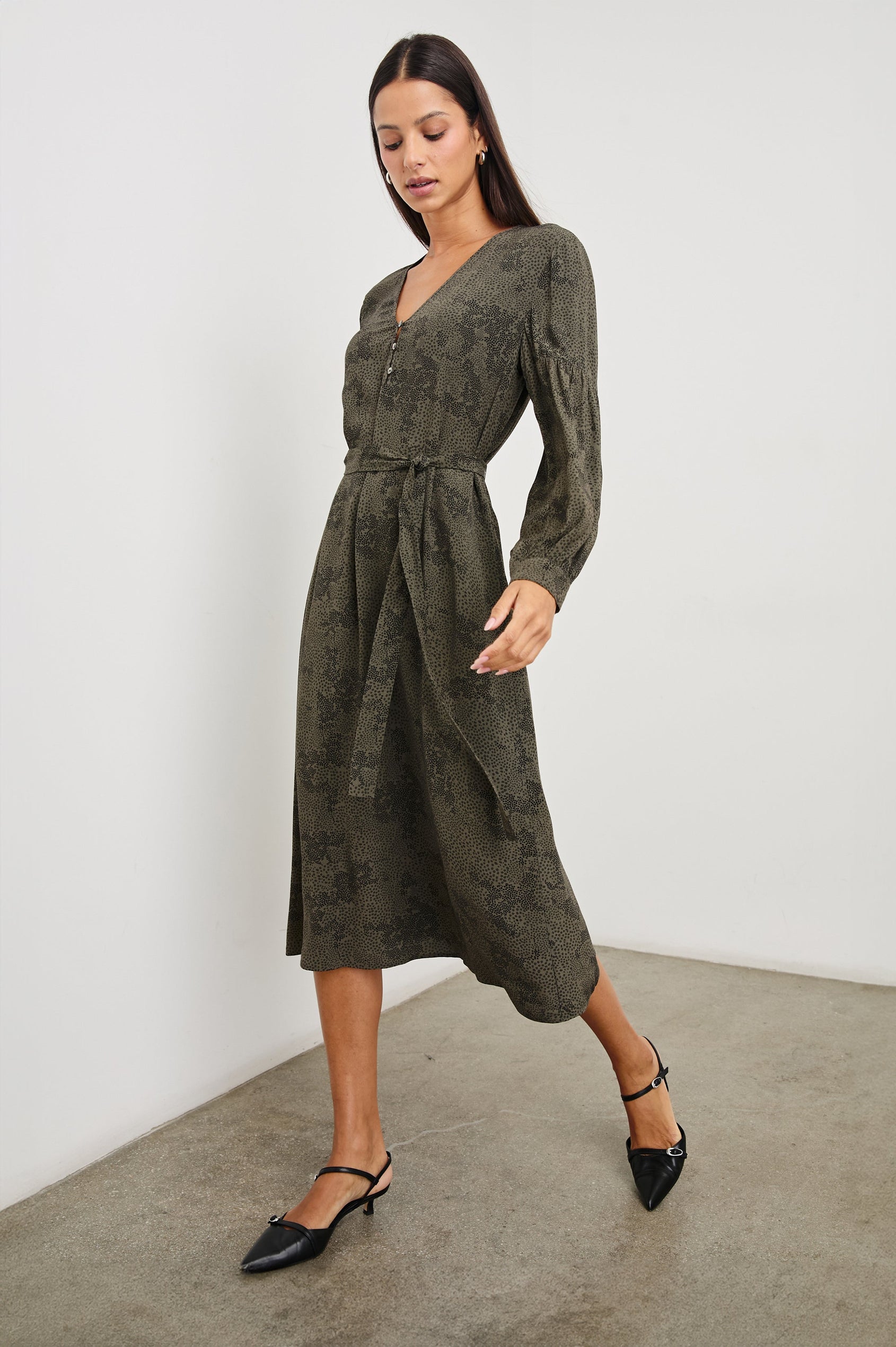 Fabian Long Sleeve Midi Dress with a V Neck with Three Buttons, a Fabric Tie at the Waist, Button Cuffs and Light Ruching on the Sleeves in Olive Pebble Colorway, Black Pebble Pattern on Olive - Front Full Body View Featured on Model