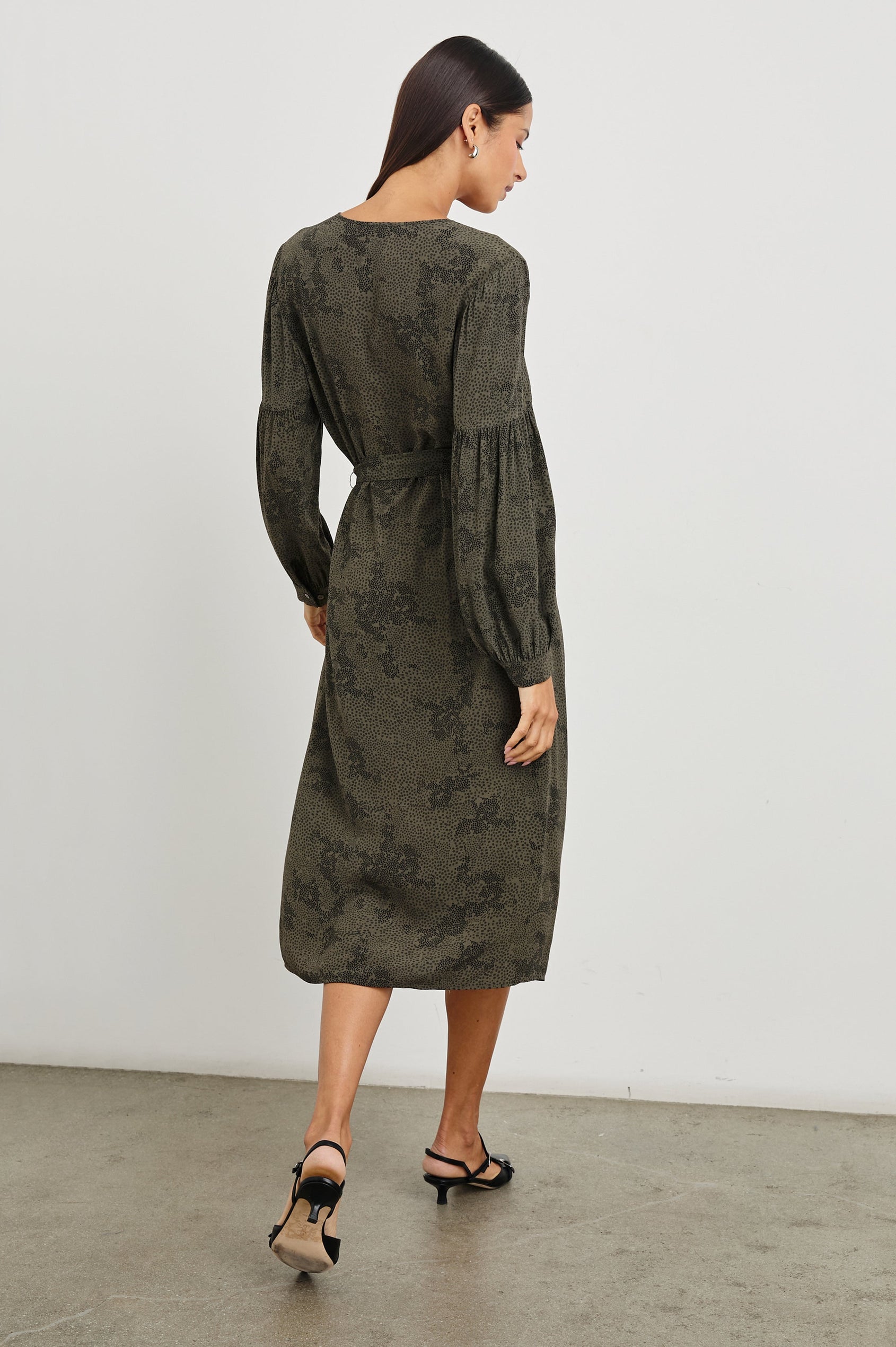 Fabian Long Sleeve Midi Dress with a V Neck with Three Buttons, a Fabric Tie at the Waist, Button Cuffs and Light Ruching on the Sleeves in Olive Pebble Colorway, Black Pebble Pattern on Olive - Back Full Body View Featured on Model