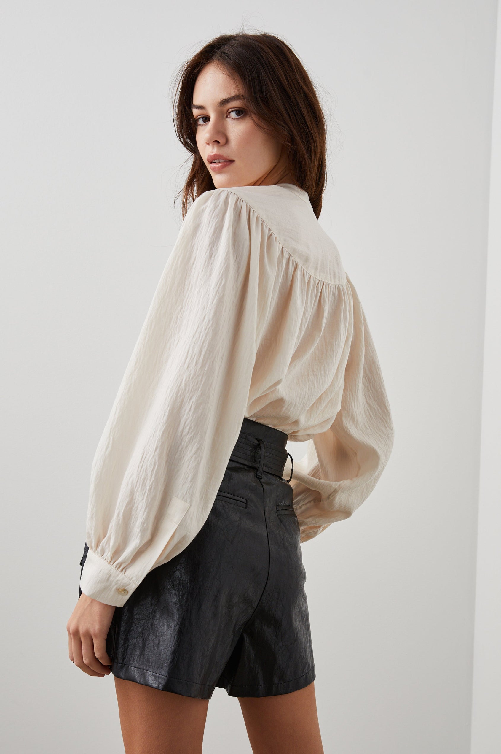 Fable Long Sleeve Top with a V Neck with a Placket, Buttoned Cuffs, and Pleating Down From the Yoke in Lotus Colorway - Back Tucked View Featured on Model 