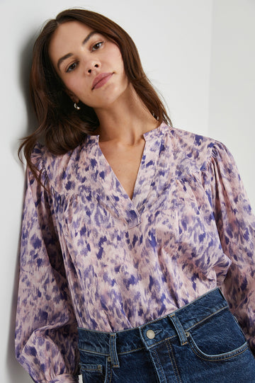 Fable Long Sleeve Top with a V Neck with a Placket, Buttoned Cuffs, and Pleating Down From the Yoke in Pink Ikat Colorway, Diffused Purple Spots on Pink - Front Tucked View Featured on Model 