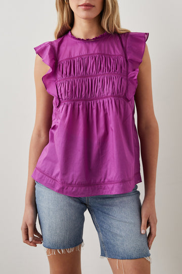 Filomena Short Sleeve Top with Flutter Sleeves, a Ruffled Neck, a Shirred Center Bodice, Lace Inserts and a Buttoned Keyhole at the Back in Berry Colorway - Front View Featured on Model