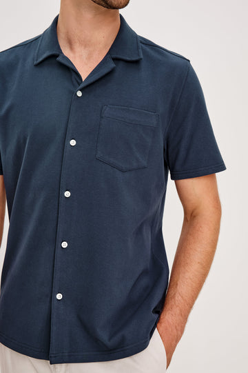 Flint Collared Button Shirt with Short Sleeves and a Chest Pocket in Perfect Navy Colorway. Front Detail View Shown on Model.