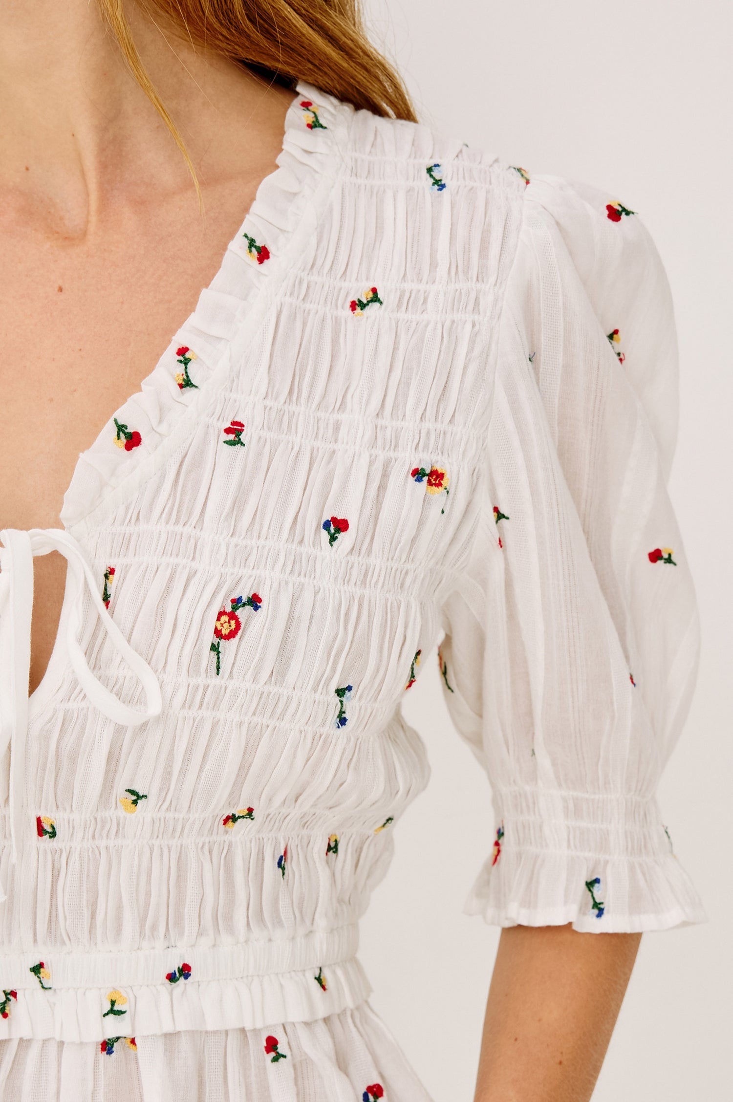 Fontaine Top in Cotton With Smocked Bodice, Self-Tie V-Neckline, Short Puff Sleeves, and Softly Flared Peplum Hem in White Wildflowers Colorway - Upper Body Front View Featured on Model