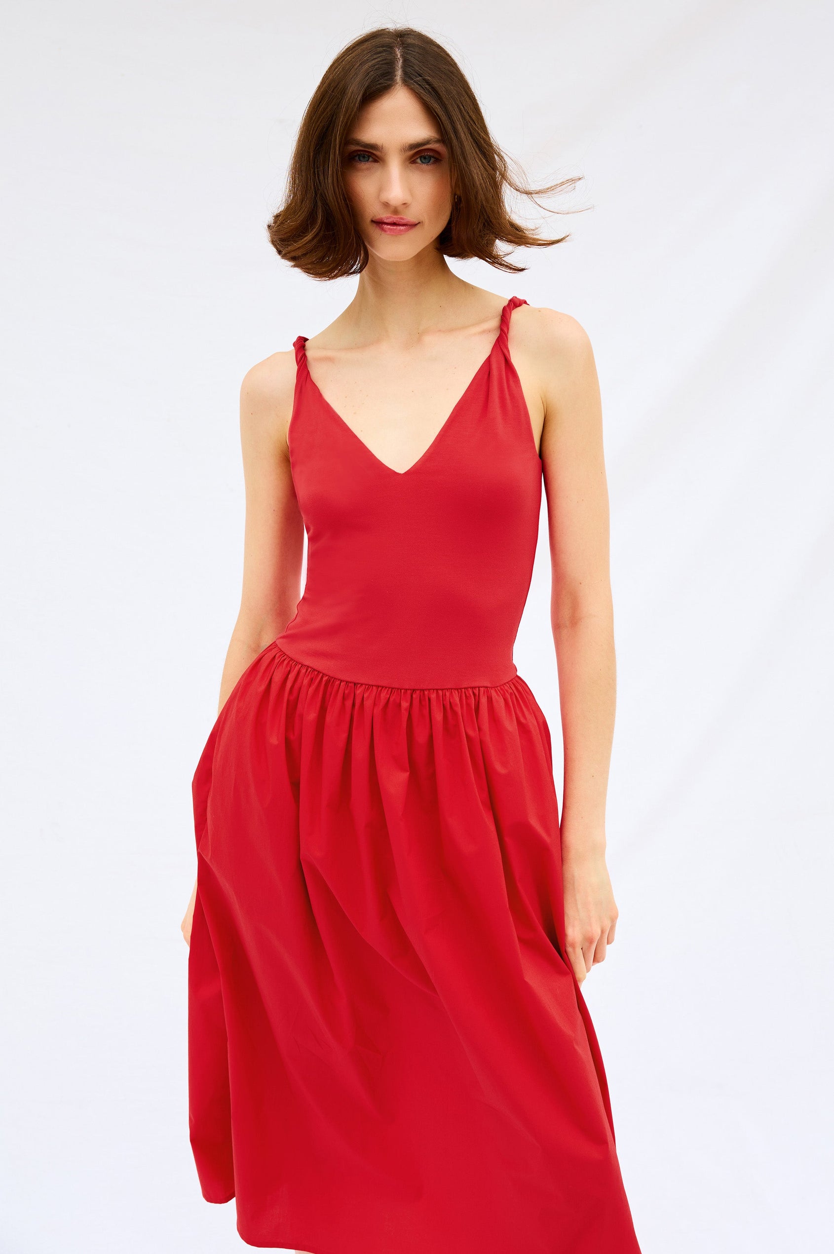 Franca Sleeveless Midi Dress with Twisted Shoulder Straps, a deep V Neck and Pleats at the Waist in Cherry Colorway - Front Body Stylized View Featured on Model