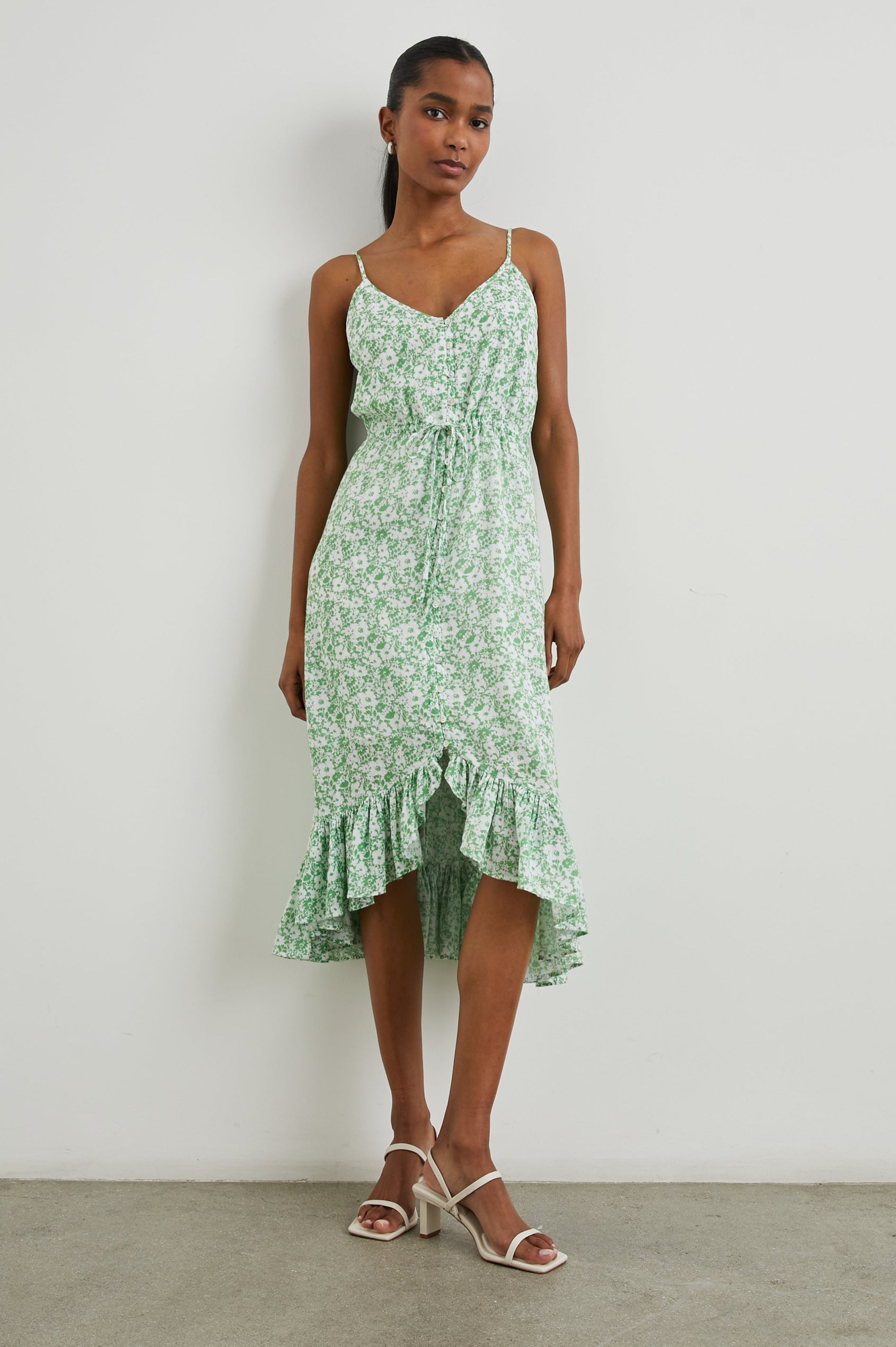 Frida Midi Dress with a Deep V Neck, Adjustable Spaghetti Straps, a Ruffled Hem, Drawstring Waist Ties and Buttons Down the Front in Green Texture Floral Colorway, Green and White Flowers - Front Full Body View Featured on Model