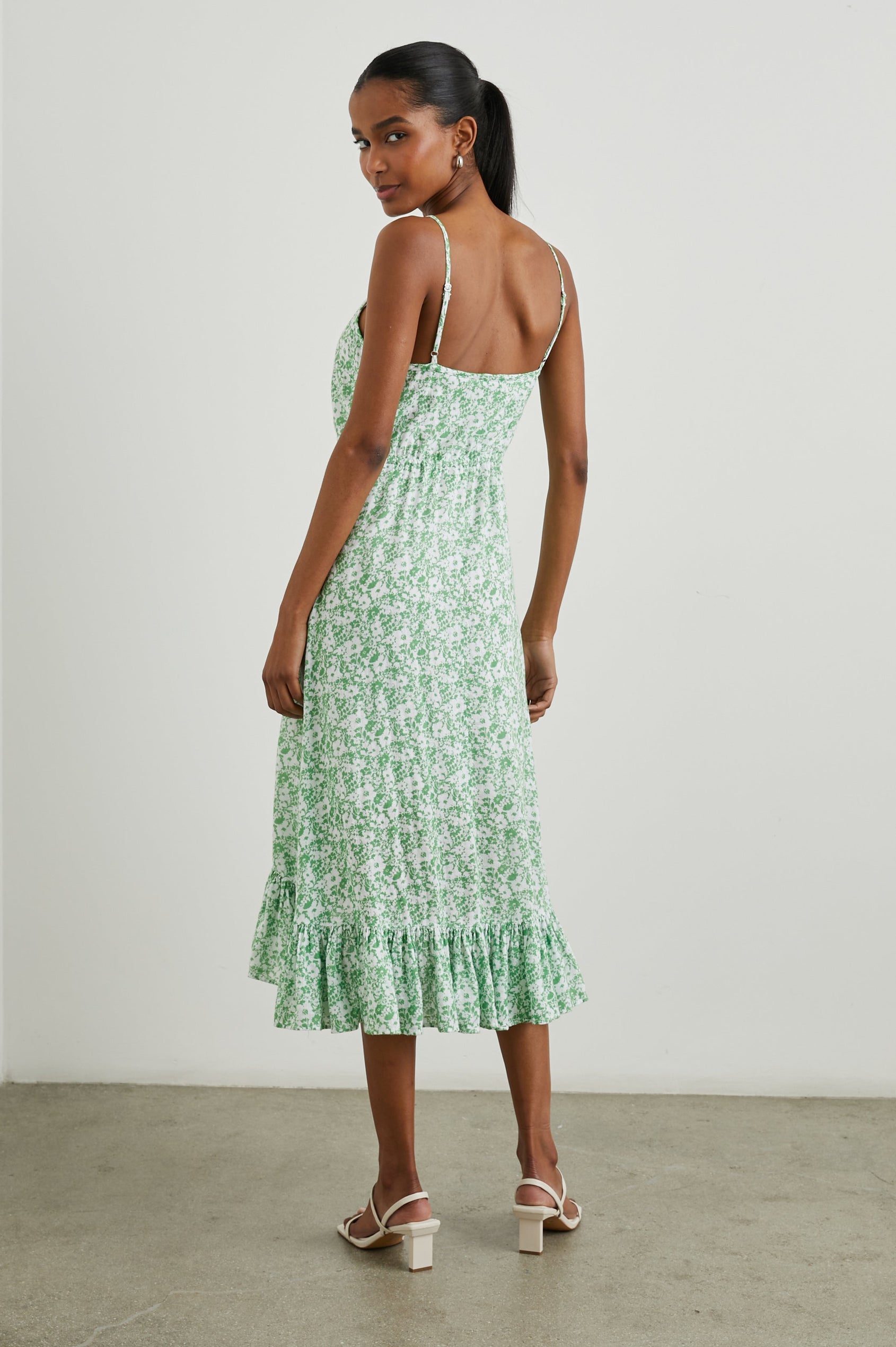 Frida Midi Dress with a Deep V Neck, Adjustable Spaghetti Straps, a Ruffled Hem, Drawstring Waist Ties and Buttons Down the Front in Green Texture Floral Colorway, Green and White Flowers - Back Full Body View Featured on Model