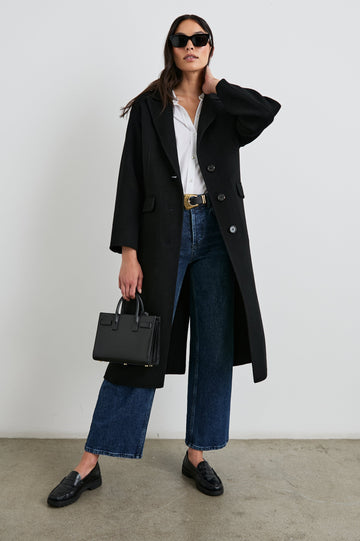 Gallery Below-the-Knee Coat with Three-Button Closure, Notched Lapels, and Two Front Flap Pockets in Black Colorway - Front Full Body View Featured on Model
