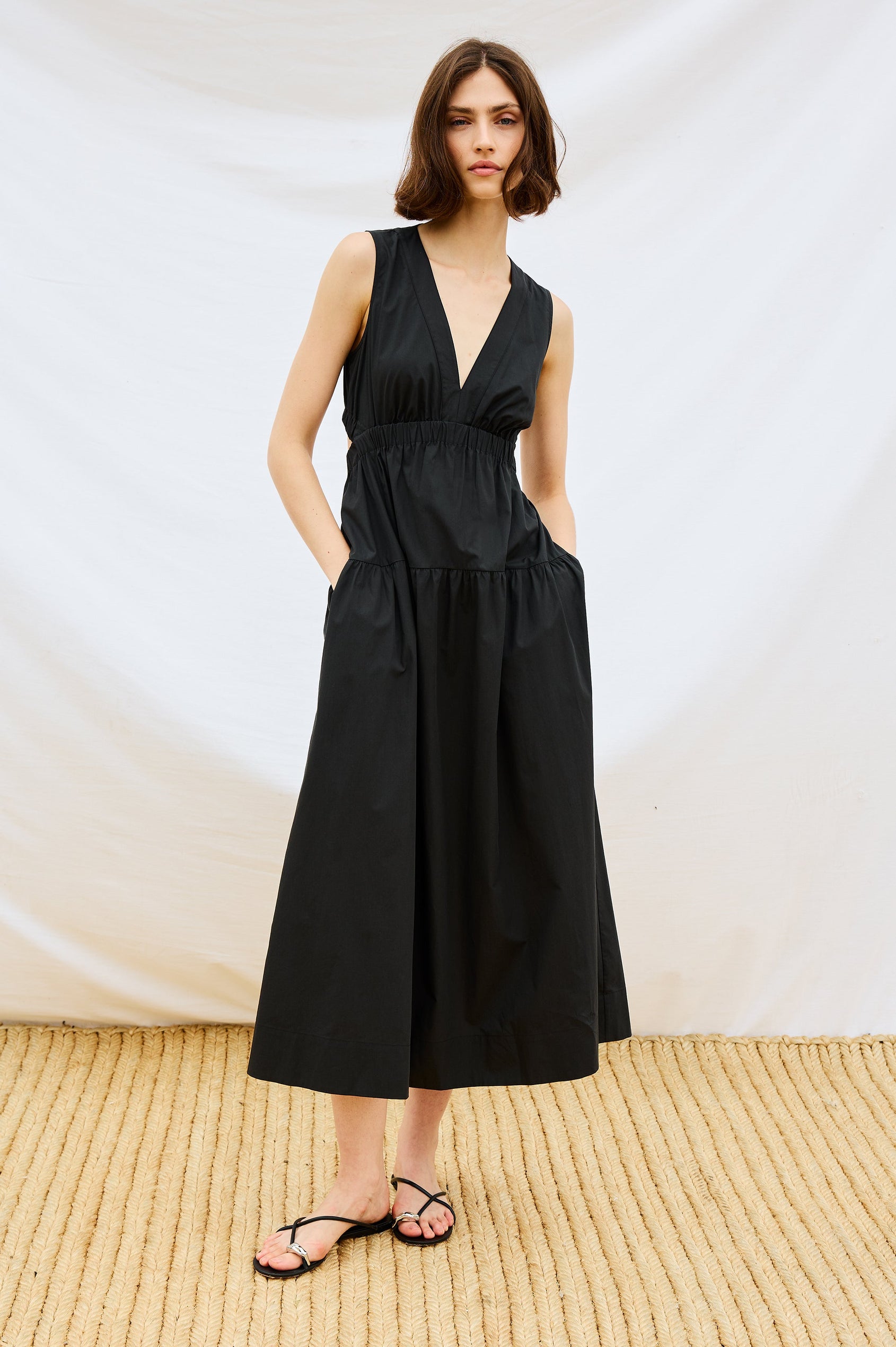 Genevieve Midi Tank Dress with Low V-Neck, Encased Elastic Waistband, Back Waist Cutout and Tiered A-Line Skirt in Black Colorway. Stylized Full Body Front View Shown on Model.