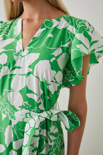 Gia Short-Sleeve Midi Dress with Flutter Sleeves, a V Neck, a Fabric Tie at the Waist, and a Tiered Skirt Green Lotus Colorway, Green and White Flowers - Front View Featured on Model