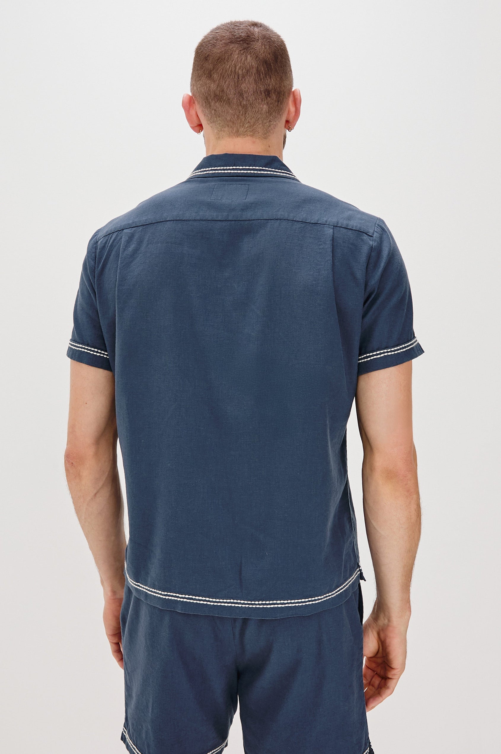 Gibson Button Front Shirt with Open Relaxed Collar, Short Sleeves, White Contrast Buttons, Contrast White Stitching at Collar and Hems and Embroidered White Palm Trees on Left Side in Navy White Palm Colorway. Back View Shown on Model.