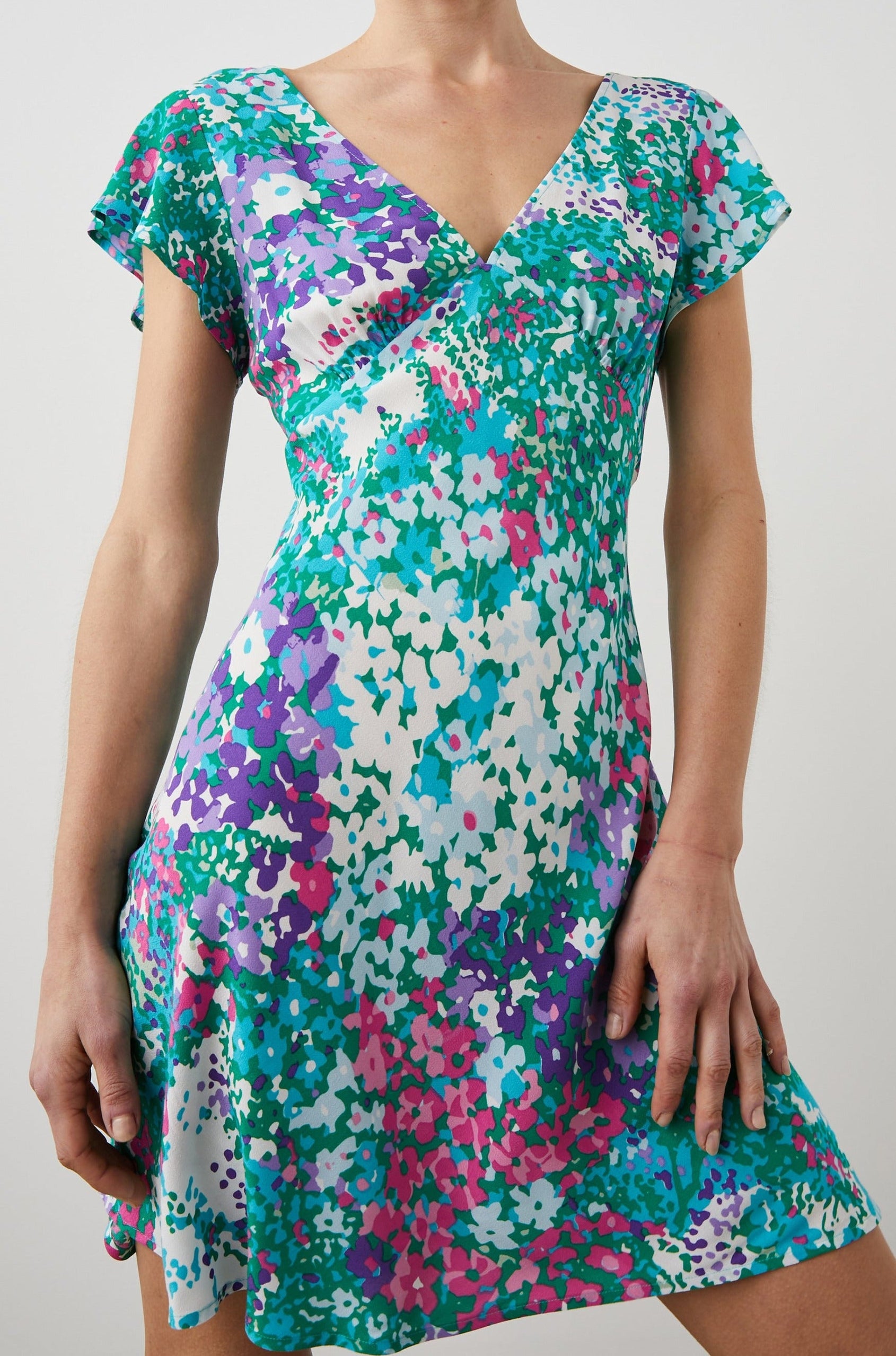 Gigi Short Sleeve Mini Dress with a Deep V Neck, and Flutter Sleeves in Gardenia Floral Colorway, Greens, Blues, Purples, Pink and White - Front View Featured on Model 