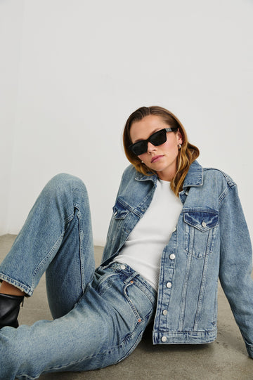 Grove Boyfriend Trucker Denim Jacket with Button Closure, Two Front Pockets, Two Chest Button Flap Pockets, Front Vertical Seams in Embossed Indigo Colorway - Front Full Body View Featured on Seated Model  