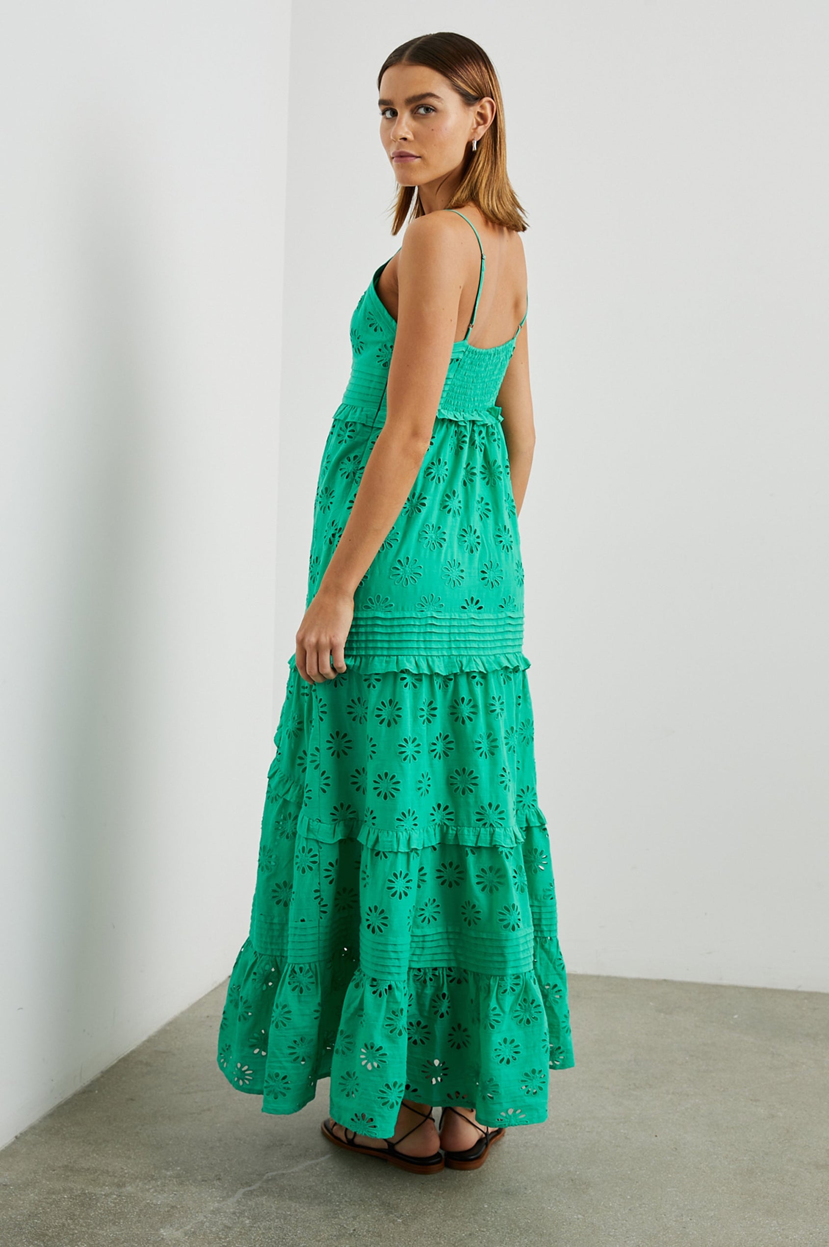 Henrietta Sleeveless Maxi Dress with Adjustable Spaghetti Straps, a Deep V Neck, Buttons Down the Front, a Shirred Back Bodice, a Tiered Skirt with Ruffles and Horizontal Pleats, and a Floral Eyelet Design in Jade Colorway - Side Full Body View Featured on Model 