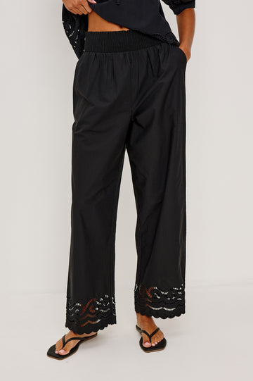Henrik High-Rise High-Waisted Pant With Wide Smocked Waistband, Side Pockets, Straight Legs, and Scalloped Ladder Embroidered Hem in Black Colorway - Lower Body Front View Featured on Model