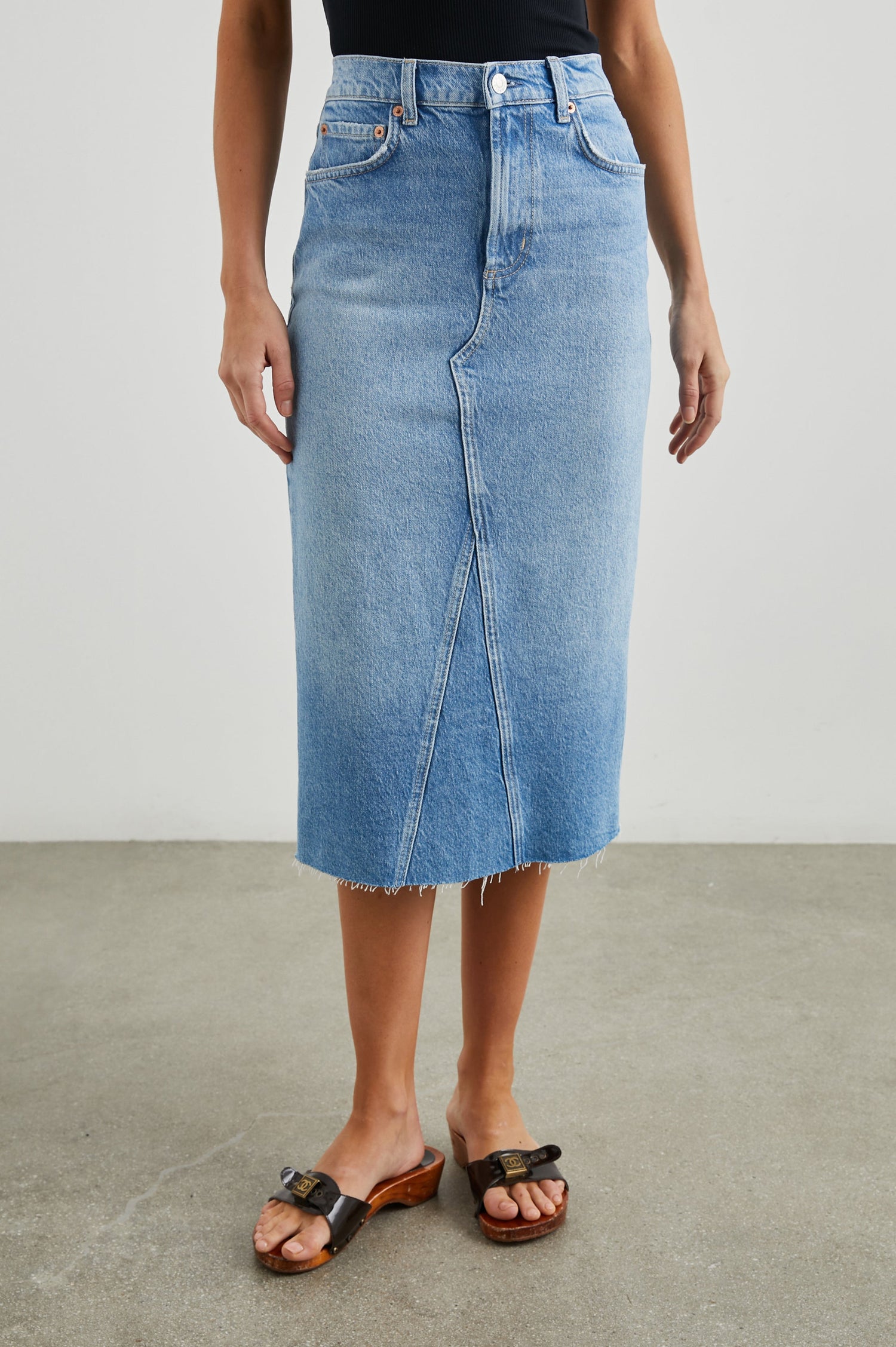 Highland Denim Midi Skirt with a Raw Hem, a Back Vent, Additional Front Seams, Belt Loops, Two Front Pockets plus a Coin Pocket and Two Back Patch Pockets in Baja Blue Colorway - Front View Featured on Model 