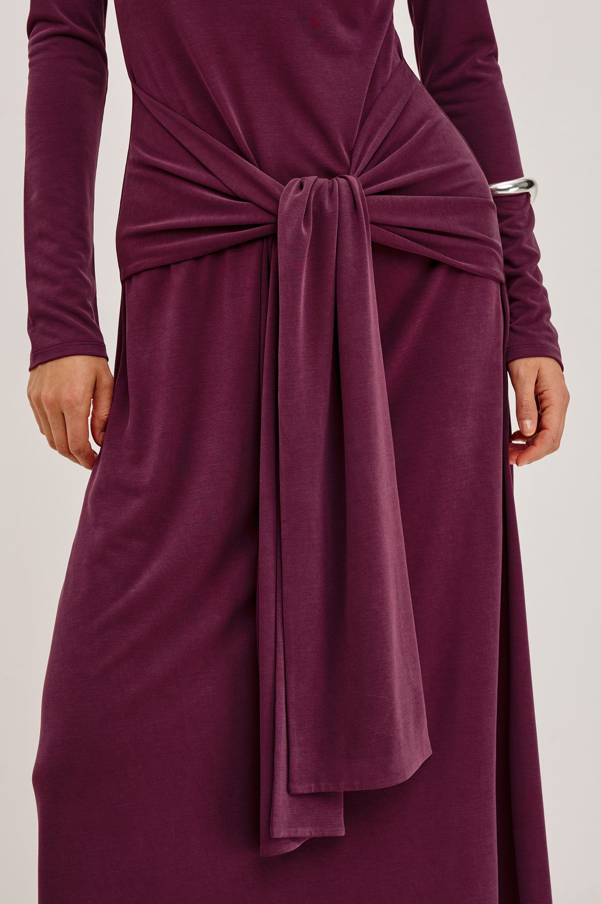 Hollis Midi Dress in Soft Jersey With Mockneck, Front Waist Ties, Pleated Shoulders, Long Sleeves, and A-Line Skirt in Wine Colorway - Upper Body Front Detail View Featured on Model.