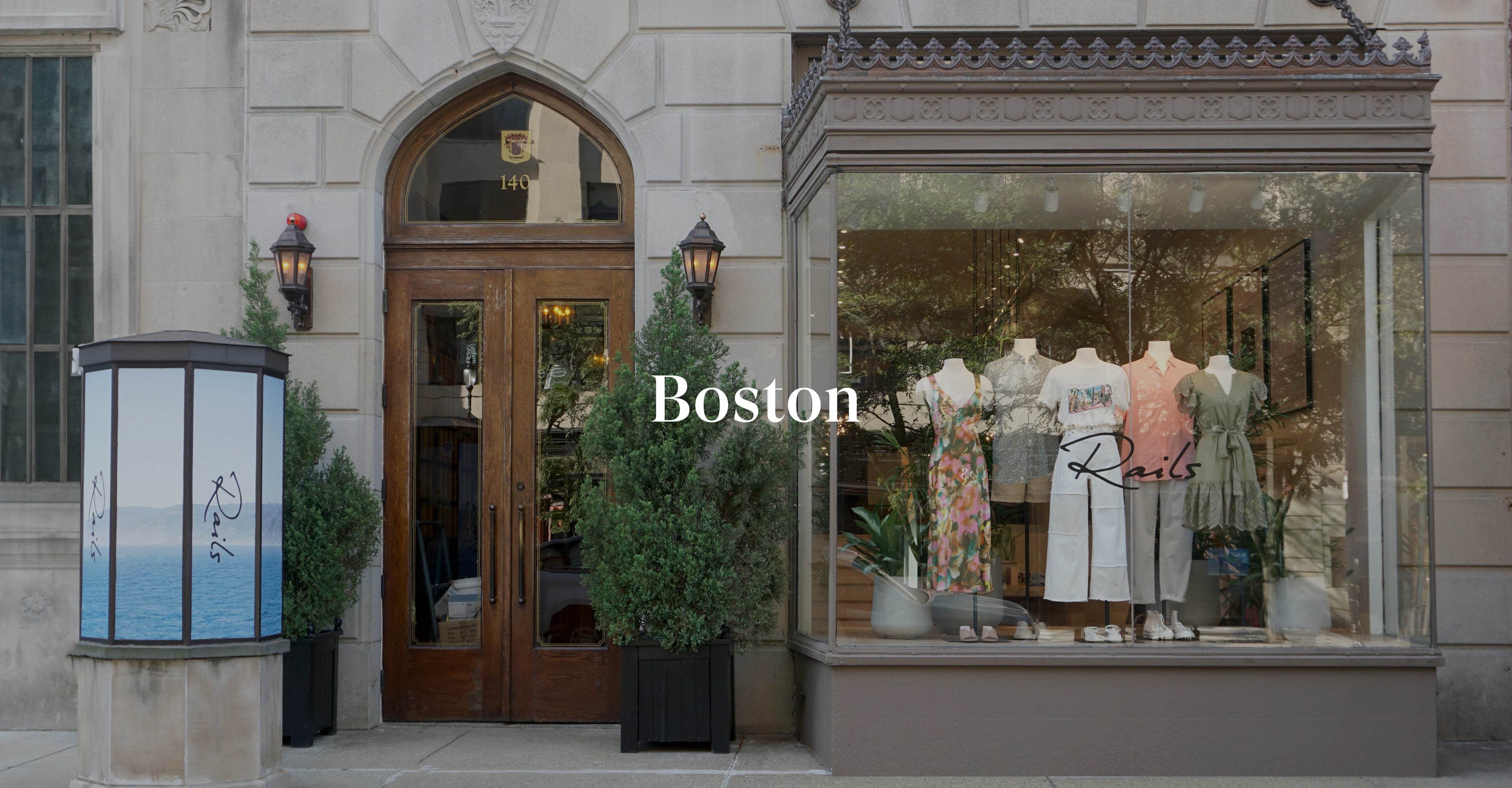 OUTSIDE OF BOSTON STORE SHOWING MAIN ENTRANCE (LARGE WOODEN DOOR) AND FRONT DISPLAY WINDOW (LARGE GLASS WINDOW WITH MULTIPLE MANIQUINS DISPLAYING CLOTHING)