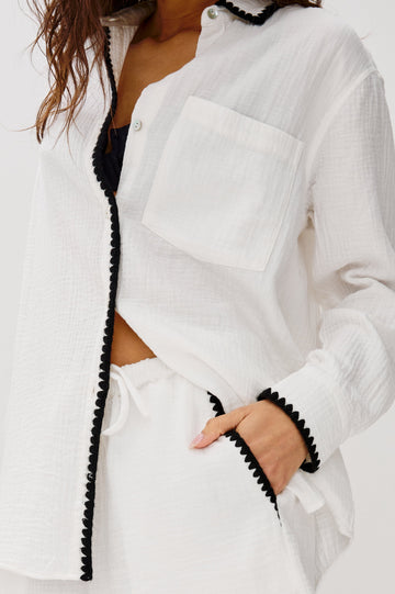 Idania Button Front Collared Shirt with Long Sleeves, Relaxed Fit and a Front Chest Pocket with a White Body in Black Blanket Stich Colorway. Close up of Details Shown on Model Buttoned Up.