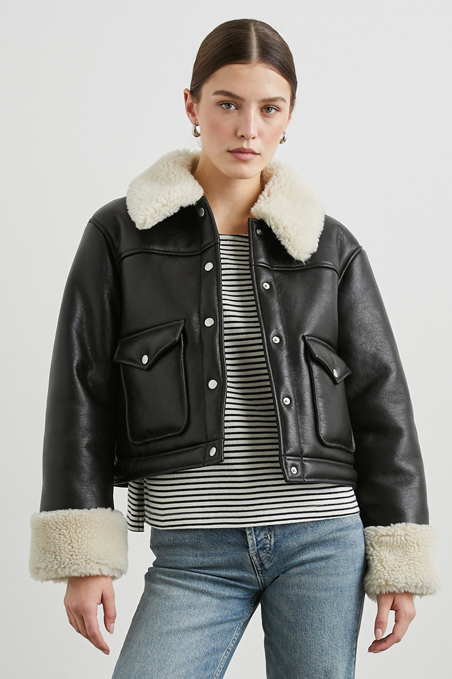 Imani Cropped Faux Leather Jacket with Silver-Toned Snap Closure, Two Front Snap Flap Pockets and Ivory Faux Shearling Lining, Collar and Cuffs in Black Ivory Colorway - Front View Featured on Model  