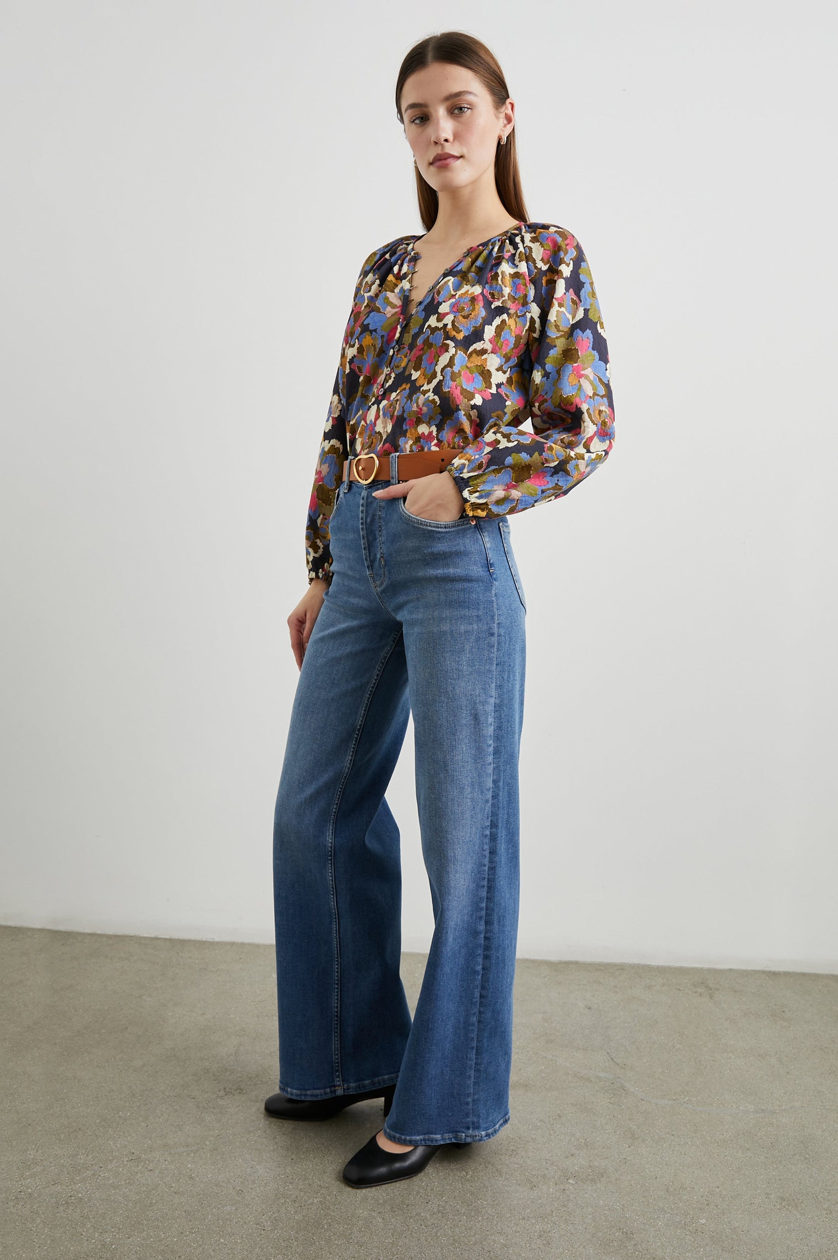 Indi Top with a V Neckline with a Button Placket, Pleating at Back Neckline and Elastic Cuffs in Navy Wildflower Colorway, with blue, gold, green and cream flowers on navy - Front tucked Full Body View Featured on Model