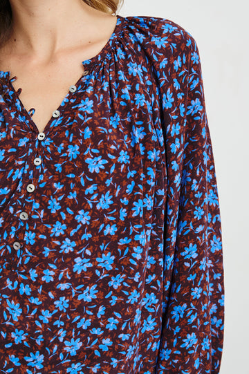 Indi Top with a V Neckline with a Button Placket, Pleating at Back Neckline and Elastic Cuffs in Russet Camellia Colorway, with russet and blue flowers - Front Untucked View Featured on Model