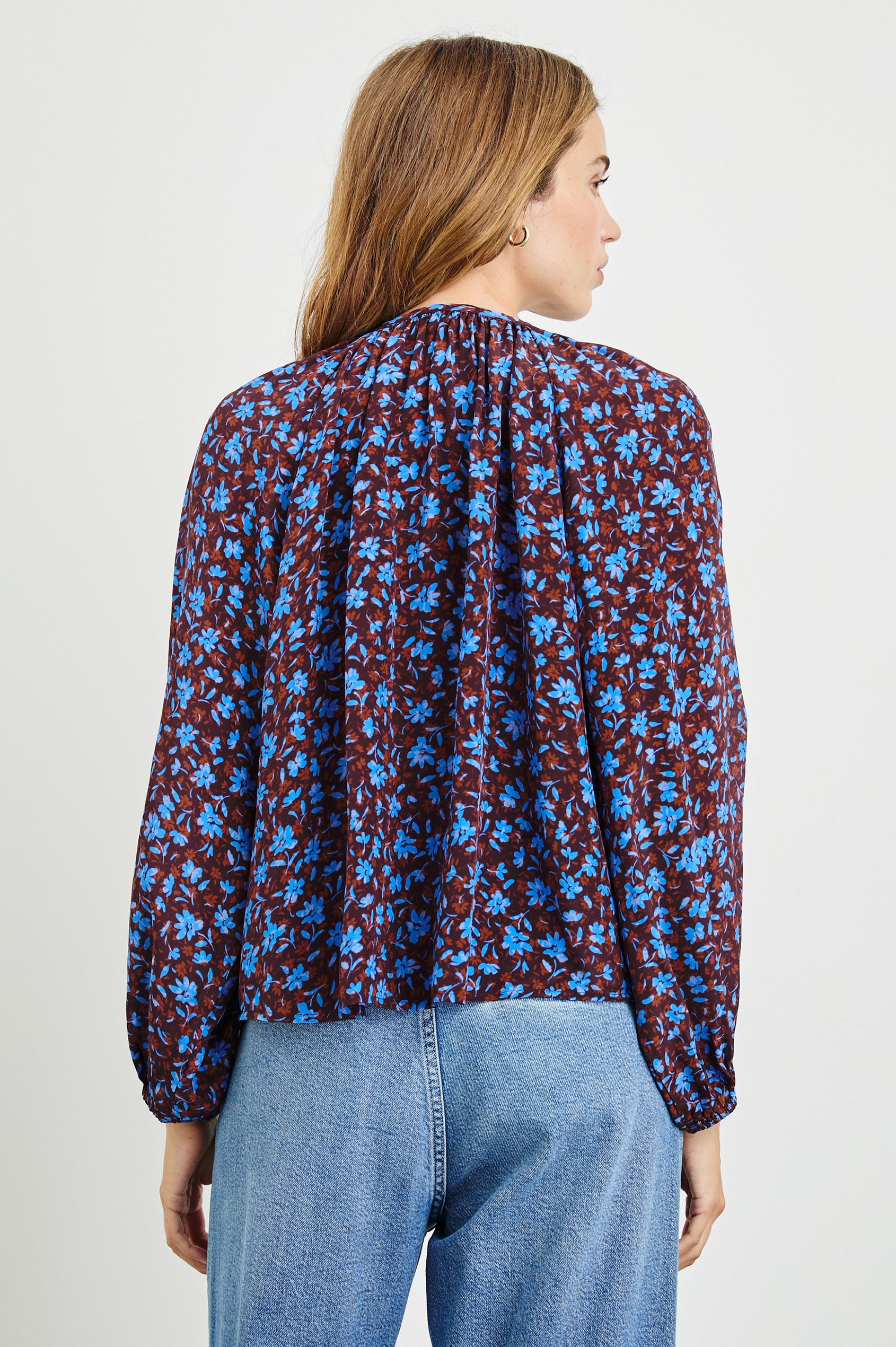 Indi Top with a V Neckline with a Button Placket, Pleating at Back Neckline and Elastic Cuffs in Russet Camellia Colorway, with russet and blue flowers - Back Untucked View Featured on Model