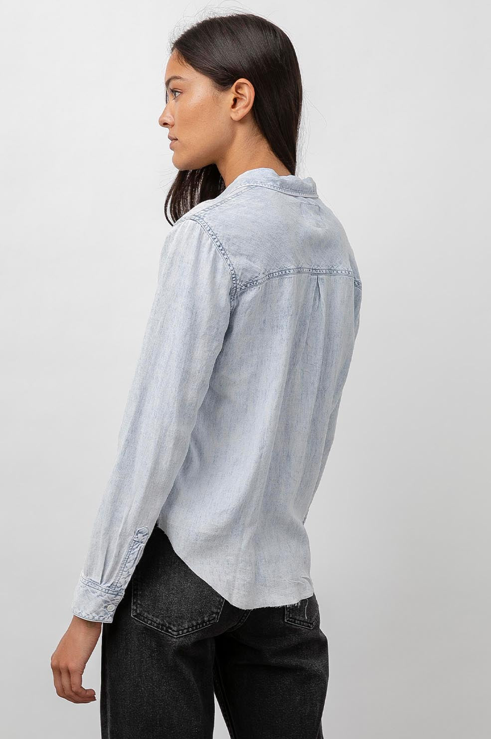 Ingrid Raw Hem, Long Sleeve Denim Button Up with a Chest Patch Pocket in Light Acid Wash Colorway - Back View Featured on Model