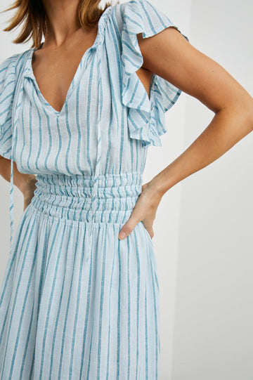 Iona Short Sleeve Midi Dress with Flutter Sleeves, a Deep V Neck with Ties, and a Shirred Waist in Cambria Stripe Colorway, Vertical Stripes in White, Blue and Light Blue - Front View Featured on Model 