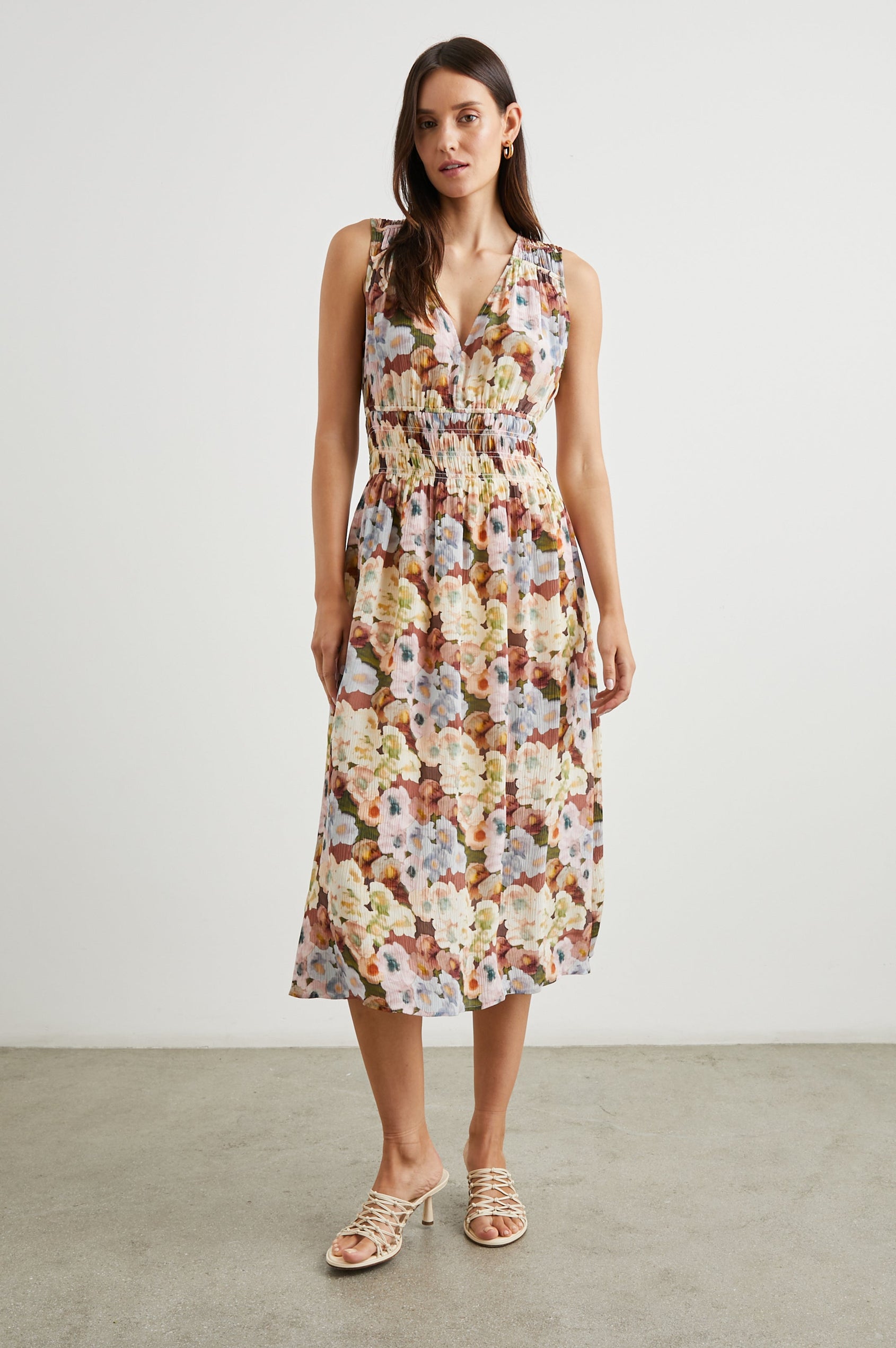 Izzy Sleeveless Midi Dress with Wide Smocked Shoulder Straps, a Smocked Waist and a Deep V Neck, in Painted Floral Colorway, in Browns, Yellows, Pinks, Blues and Greens - Front Full Body View Featured on Model 