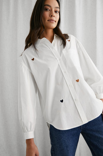Janae Long Sleeve Button Up with a Chest Patch Pocket, Light Ruching at the Cuffs and Sleeve Shoulder and Cutout Hearts in White Eyelet Hearts Colorway - Front View Featured on Model 