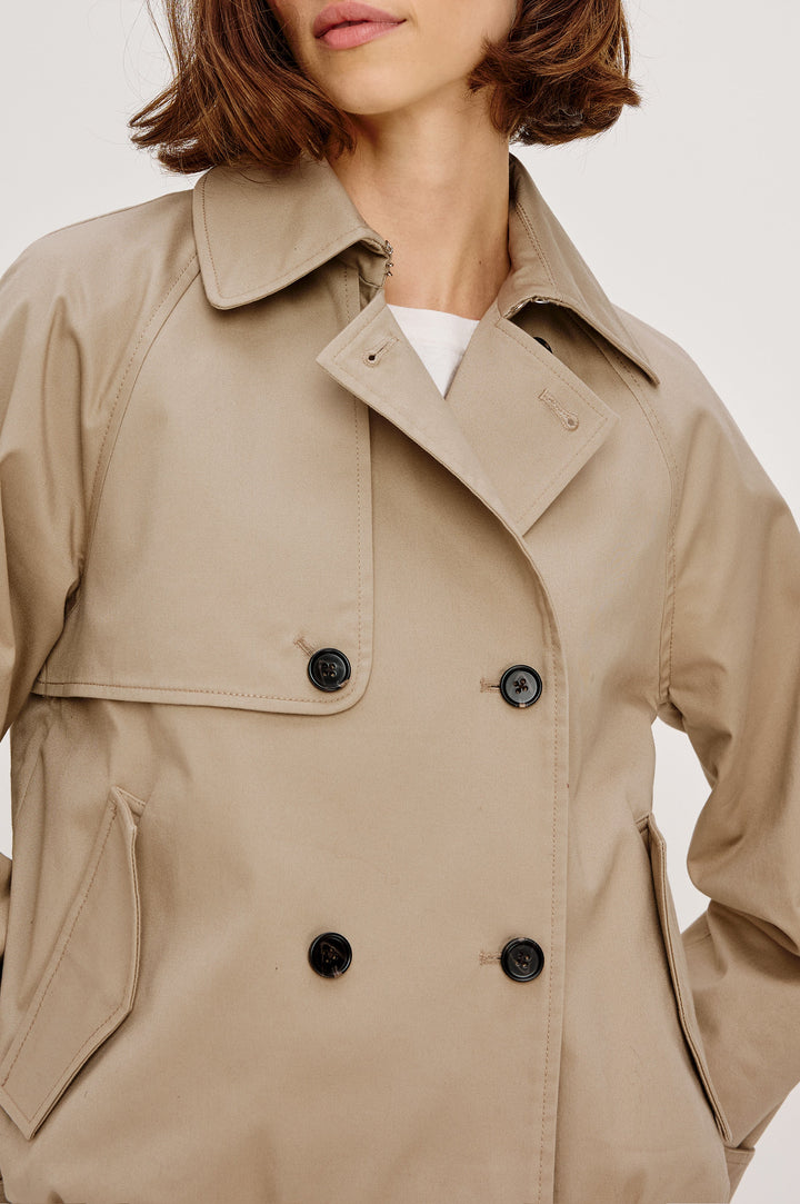 Jett Double Breasted, Cropped Trench Jacket, Lapel, Adjustable Cuff Belt, Side Pockets and Elasticated Hem in Taupe Colorway. Front Detail View Featured on Model.