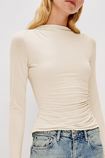 Joelle Long Sleeve Top with An Asymmetrical Mock Neck and Shirring on the Right Shoulder in Ivory Colorway - Close Up View Featured on Model