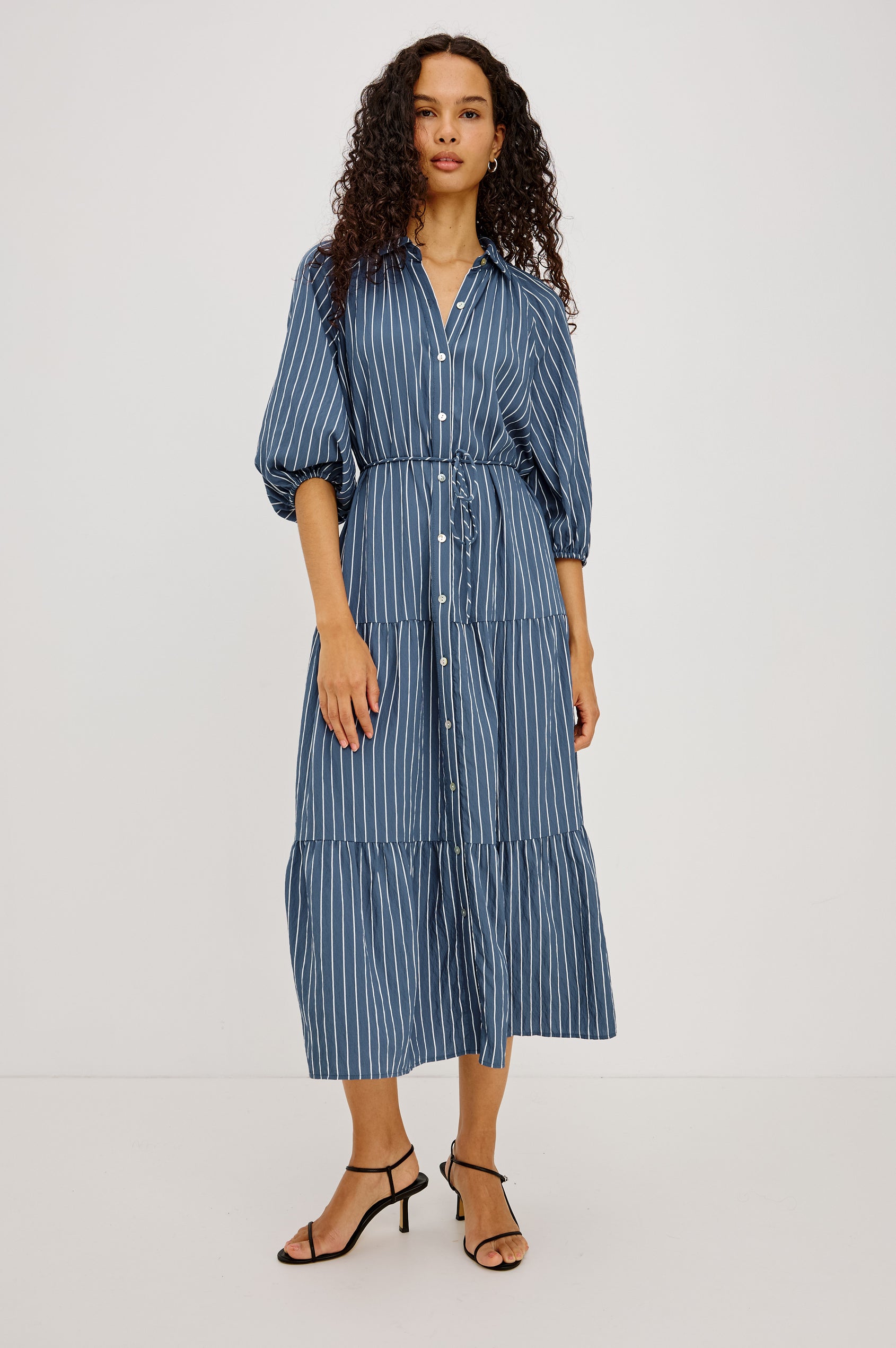 June Maxi Dress in Soft Crinkle Shirting With Three-Quarter Puff Sleeves, Point Collar, Full Front Button Placket, and Self-Tie Waist in Washed Indigo Stripe Colorway - Full Body Front View Featured on Model
